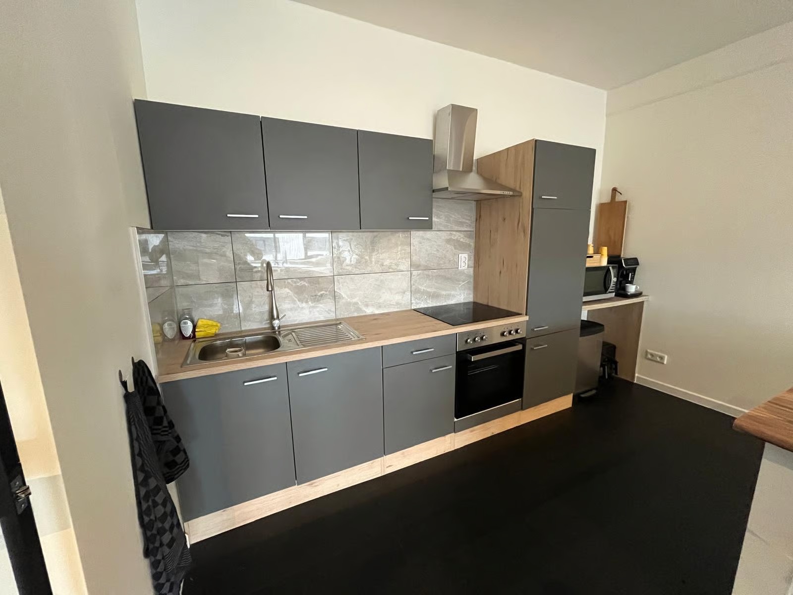 Werkruimte met schermen, keuken en lounge op de achtergrond